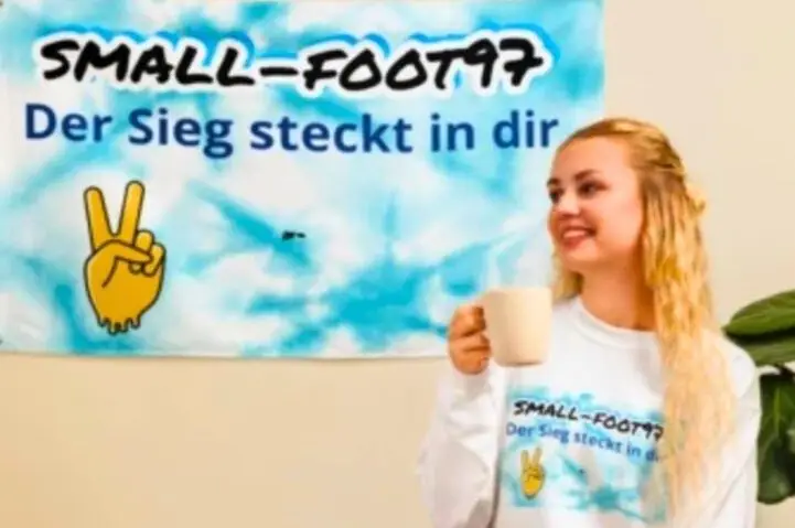 Djevojka sjedi di na stolici i gleda u zastavu na kojoj Pise nas logo Small-foot97